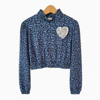 Vista frontale top ragazza blu maniche lunghe sbuffette spilla cuore ricami